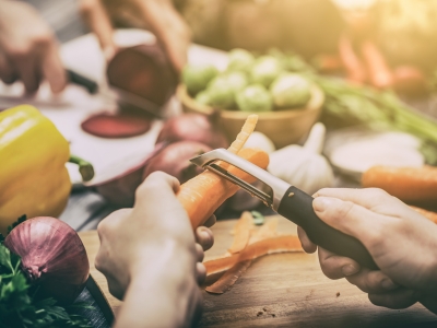 People peeling and cutting vegetables at a table.